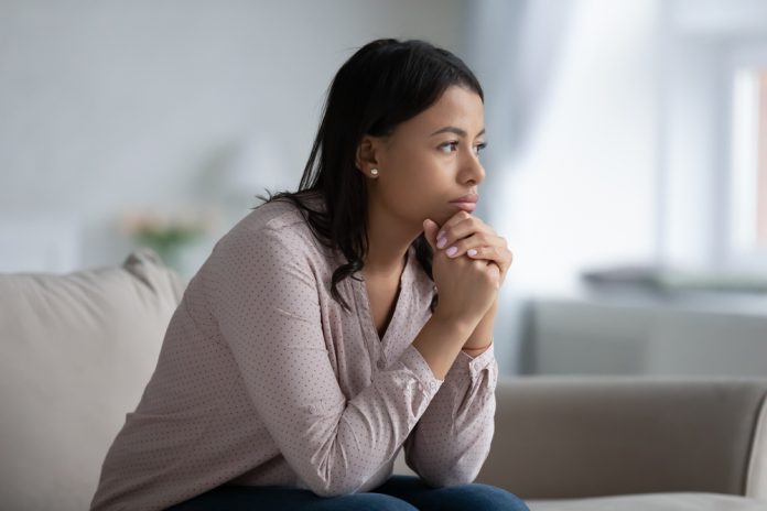 Concerned,Sad,African,Woman,Sit,On,Sofa,In,Living,Room