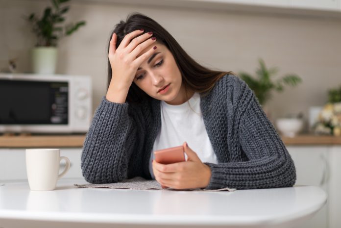 Stressed,Woman,Reading,Something,On,Her,Cell,Phone,At,Home